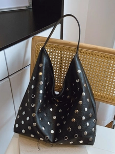 Sac hobo chic en cuir noir avec rivets argentés suspendu à une chaise en bois