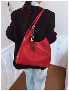 Detail of red hobo shoulder bag with bohemian beaded tassel charm and silver buckle strap