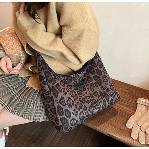 Dettaglio della borsa tote leopardata con bordo in pelle nera ed etichetta logo