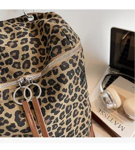 Detailansicht des Canvas-Rucksacks mit Leopardenmuster, Doppelreißverschluss und Lederanhängern