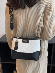 Checkerboard embossed bucket bag with adjustable wide strap shown on model's shoulder