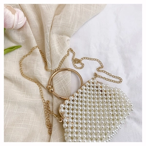Detail of handmade pearl beaded handbag with gold metal handle and luxury texture