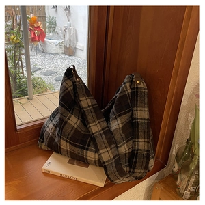 Detail of a large contrast wool tote bag with leather strap on a warm wooden windowsill