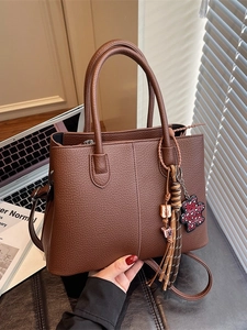 Minimalist brown leather tote bag with stylish leopard bear pendant and dual handles