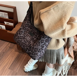 Dettaglio della borsa tote leopardata retrò con etichetta nera del marchio e tracolla robusta