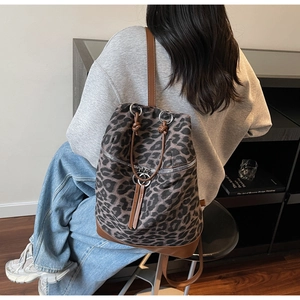 Detail eines Canvas-Rucksacks mit Leopardenmuster, braunem Lederbesatz und Silberbeschlägen