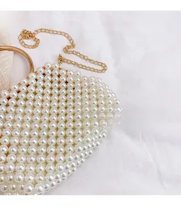 Detail of handcrafted pearl handbag with gold circular metal handle and chain strap