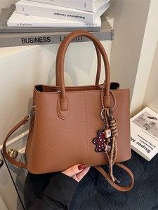 Brown litchi grain tote bag with double handles and a red bear charm pendant