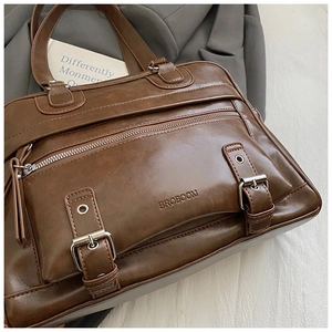 Macro shot of vintage brown leather pillow bag featuring front zipper and metal buckle details