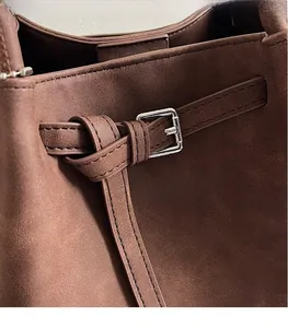 Detailed macro view of dark brown suede bag texture with silver buckle and stitching
