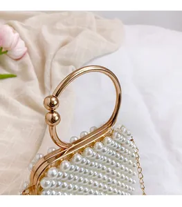Detailed close-up of handmade pearl handbag with golden metal frame and circular handle