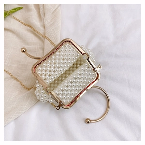 Detail of handmade pearl beaded handbag with gold metal frame and detachable chain strap