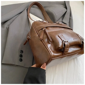 Detailed close-up of brown vintage PU leather shoulder bag with zipper pockets