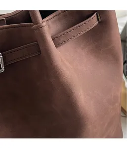 Close-up of brown suede tote bag featuring reinforced stitching and silver metal hardware