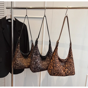 Three stylish leopard print hobo shoulder bags in brown, grey, and orange on a rack
