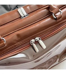 Detailed close-up of smooth double silver zippers on a large brown leather shoulder bag
