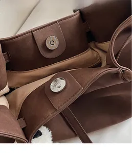 Close-up of brown matte leather handbag featuring a magnetic snap closure and neat stitching