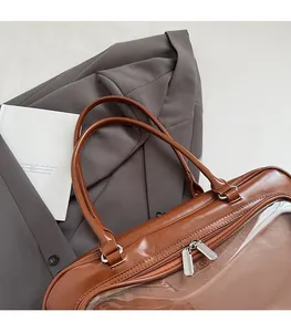 Detail view of caramel glossy handbag with clear PVC window and silver dual zippers