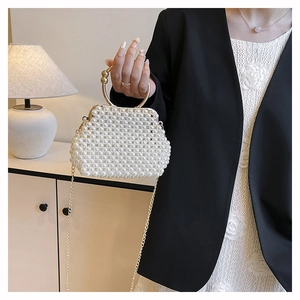Detail of handcrafted pearl beaded handbag with golden metal handle and fine chain strap