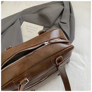 Detailed top view of dark brown leather pillow bag with silver metal zipper closure
