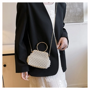 Detail of elegant handmade pearl beaded handbag with gold circular handle and gold chain strap