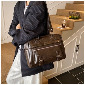 Detail of vintage dark brown faux leather pillow bag with metal buckles and zipper pockets