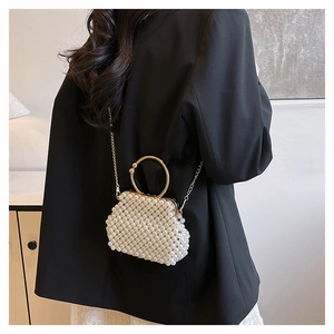 Detail view of a handmade white pearl beaded handbag with elegant golden metal ring handles