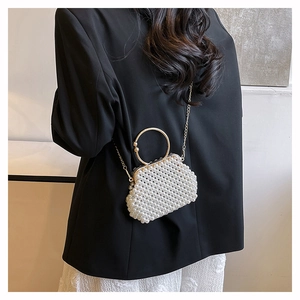 Exquisite pearl beaded handbag with gold circular metal handle shown on a model