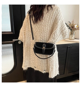 Detail view of a black frosted crossbody bag worn with a beige knitted sweater