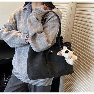 Close-up of black matte tote bag with decorative buckle and white plush puppy charm