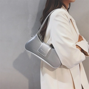 Silver metallic leather shoulder bag shown against a white suit for a chic urban look