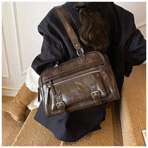 Detailed view of dark brown PU leather pillow bag with retro buckles and shoulder strap