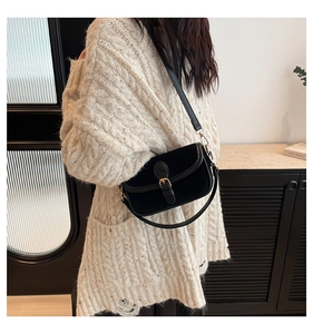 Close-up of black velvet underarm bag with vintage gold buckle on a knit sweater