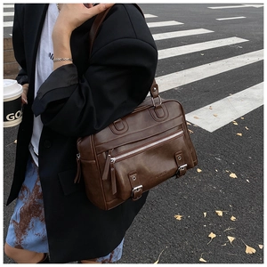 Detail of vintage brown leather pillow bag with metal buckles and front zipper pocket
