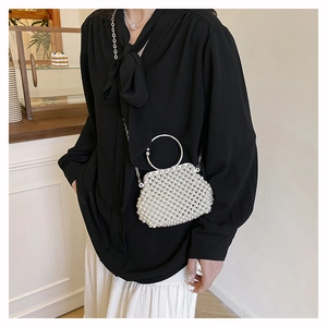 Detail of handmade pearl beaded handbag with silver ring handle and chain strap