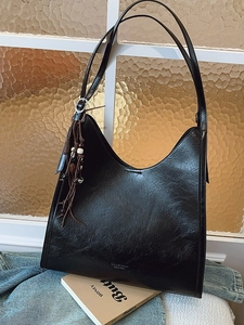Retro black leather tote bag with beaded tassels on vintage textured background
