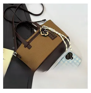 Close-up of canvas tote bag with brown leather base and stylish chocolate charm details