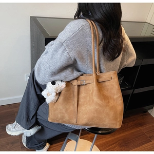 Detail of tan suede tote bag with adjustable buckle strap and white plush puppy charm
