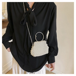 Detail of elegant handmade pearl beaded handbag with silver metal ring handles