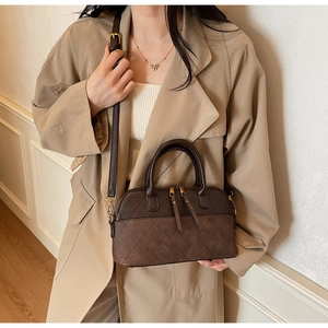 Close-up of quilted shell bag in dark brown with dual handles and gold zippers