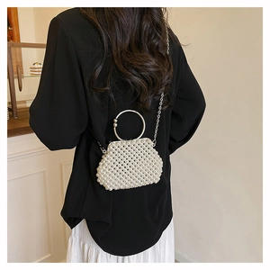 Detail of elegant pearl beaded mini handbag featuring silver round handle and chain strap