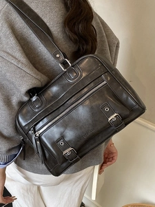 Retro black pillow shoulder bag with polished leather finish and dual metal buckles