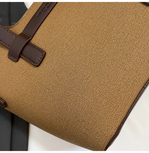 Close-up of khaki canvas fabric and brown leather strap details on a stylish handbag