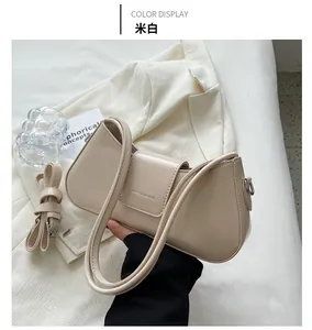 Detail of cream structural shoulder bag with flap closure and adjustable strap on a blazer