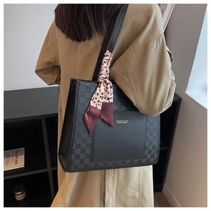 Detail of black tote bag with checkered panels and a leopard silk scarf on the strap