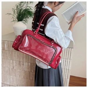 Detail view of red vintage tote bag with clear window and polished leather texture