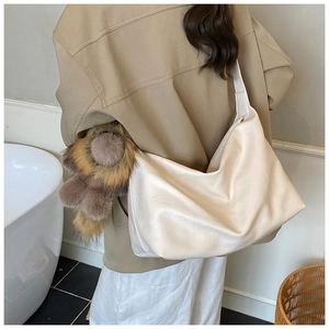 Close-up of off-white large capacity tote bag with a brown plush monster charm on side