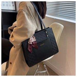 Detail of black plaid leather tote bag with gold logo and decorative leopard silk scarf