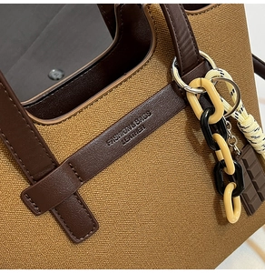 Detail view of canvas crossbody bag featuring leather straps and fashion lettering