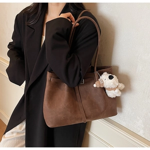 Close-up of retro dark brown faux leather tote bag with cute white plush bear pendant